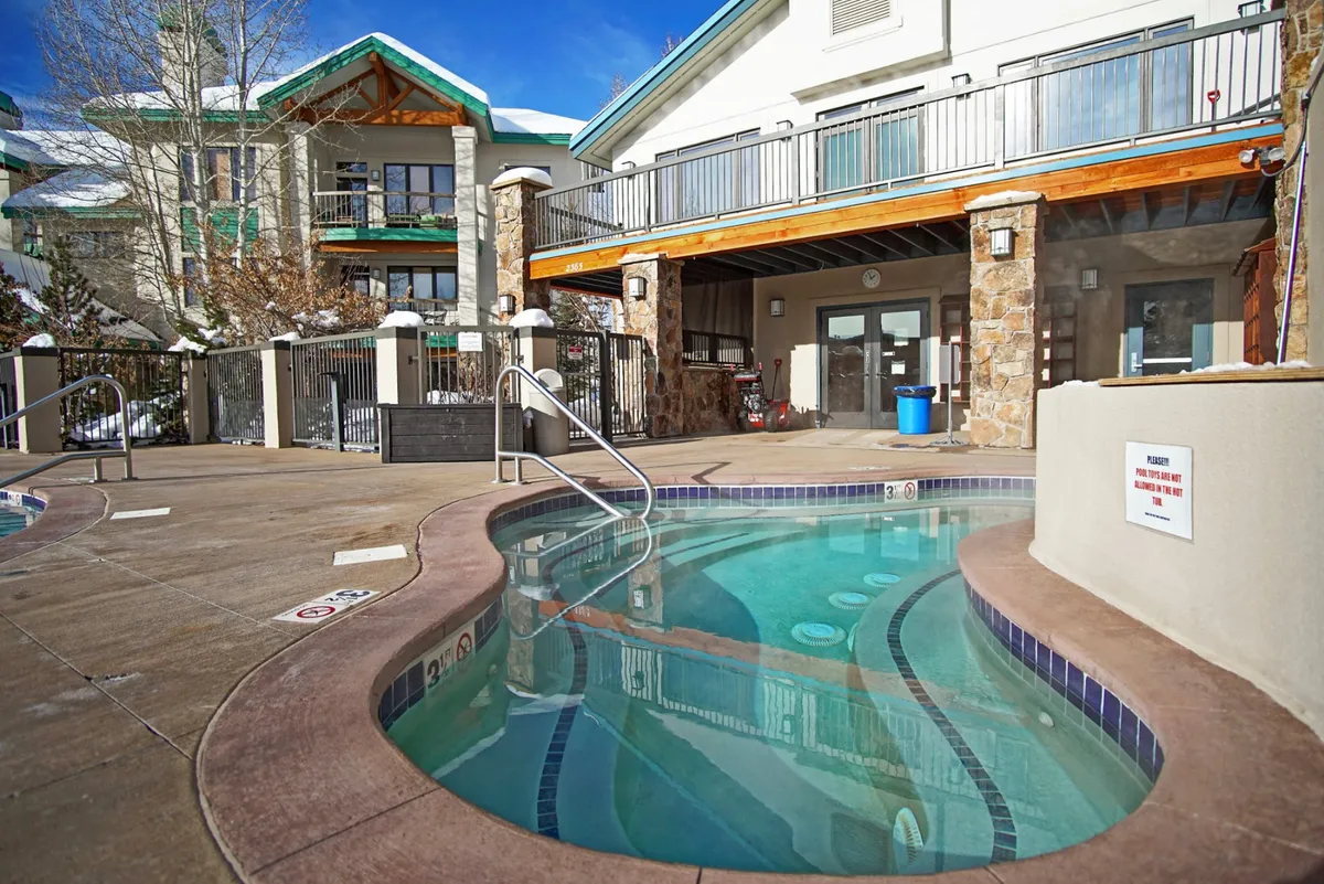 Shows a steaming hot tub on a deck area, framed by the surrounding resort architecture. The ambiance invites relaxation and socializing after a day of exploring or working remotely.