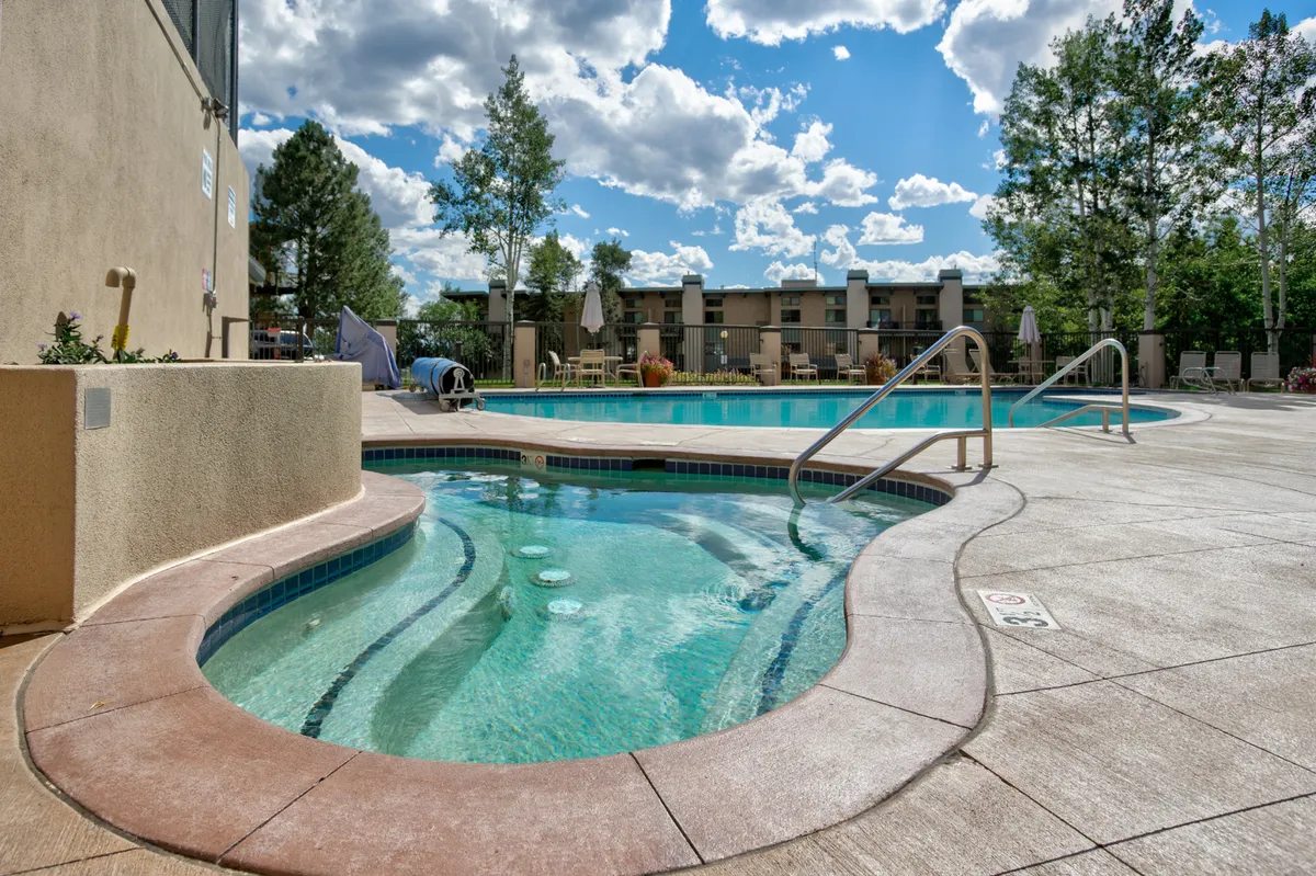 A heated outdoor swimming pool and hot tub are surrounded by trees and lounge chairs, creating an inviting recreation area. The setting blends relaxation with social fun, echoing the communal amenities described in the section.