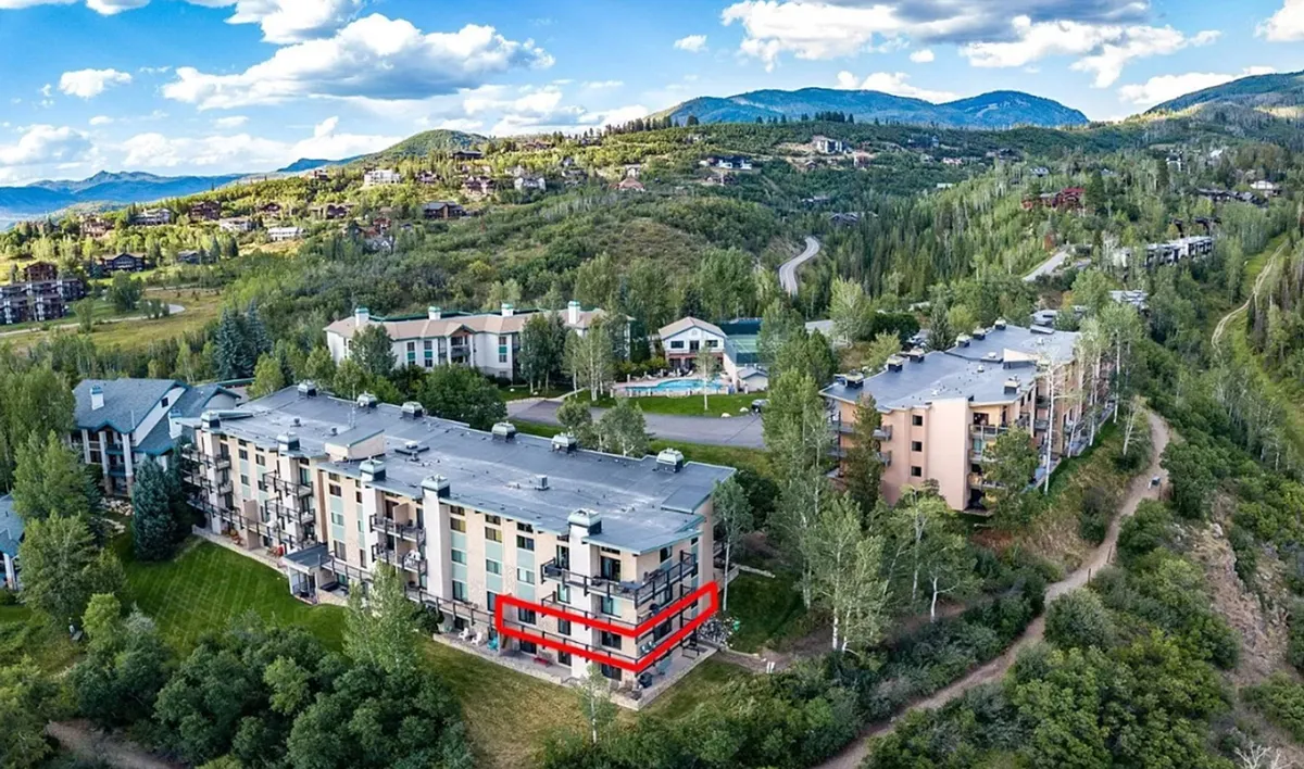 A spacious wraparound balcony highlighted against a backdrop of lush greenery and distant mountains. The balcony offers ample seating, inviting guests to relax and enjoy the serene outdoor setting. The view hints at sunrise or sunset gatherings, making it a perfect spot for evening cocktails or morning coffee while watching hot air balloons or local fireworks.